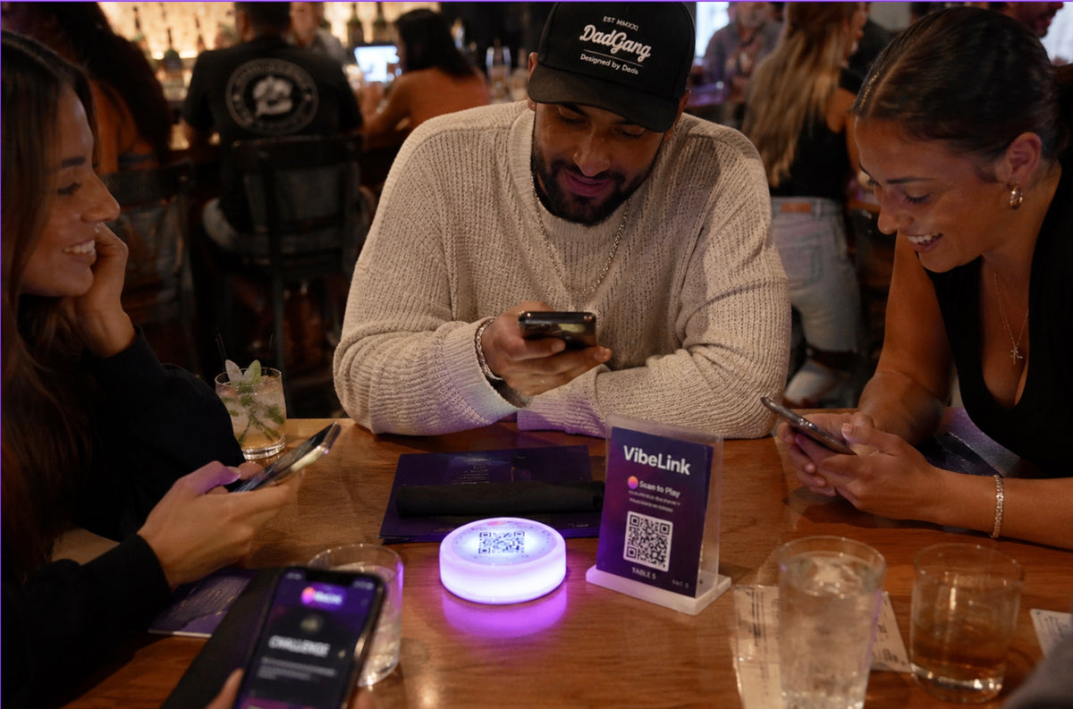 Guests connecting at a table with a VibeLink light and QR stand